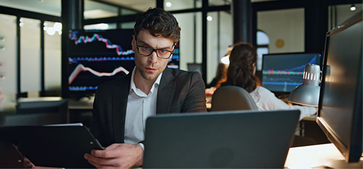 hedge fund accountant monitors accounts on laptop and tablet